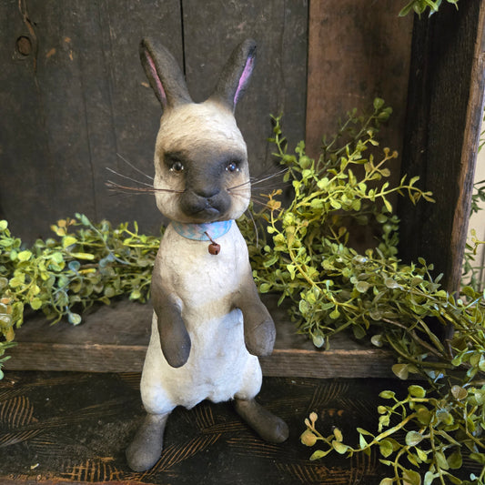 Paper mache rabbit with green foliage in the background