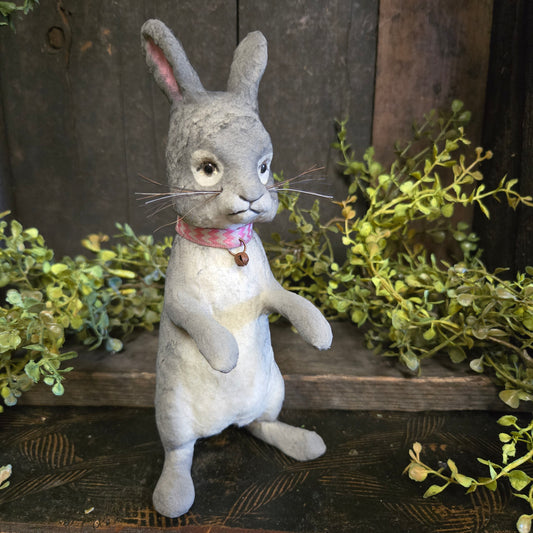 Paper mache rabbit with a wooden background and greenery