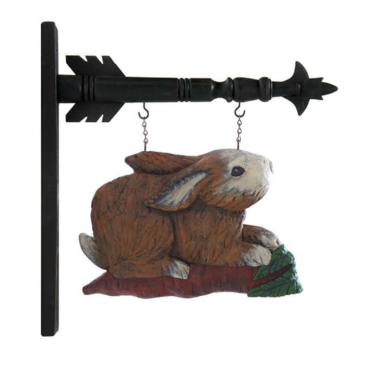 A decorative arrow replacement featuring a wooden carving of a rabbit sitting on a carrot, with brown, beige, white, and green colors, mounted on a black arrow-shaped metal rod.
