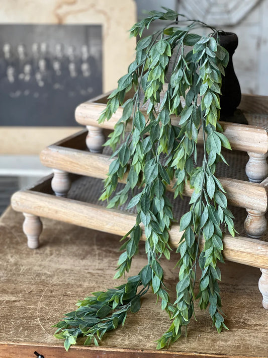 Artificial greenery hanging over a wooden staircase