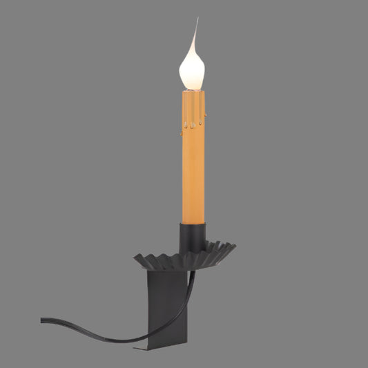 Black metal candle holder with a lit candle on a white background