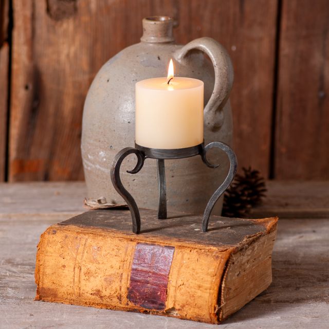 Candle in a metal holder on an old book with a rustic background