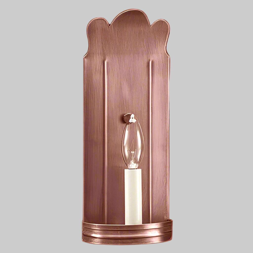Copper wall sconce with a clear glass shade on a gray background