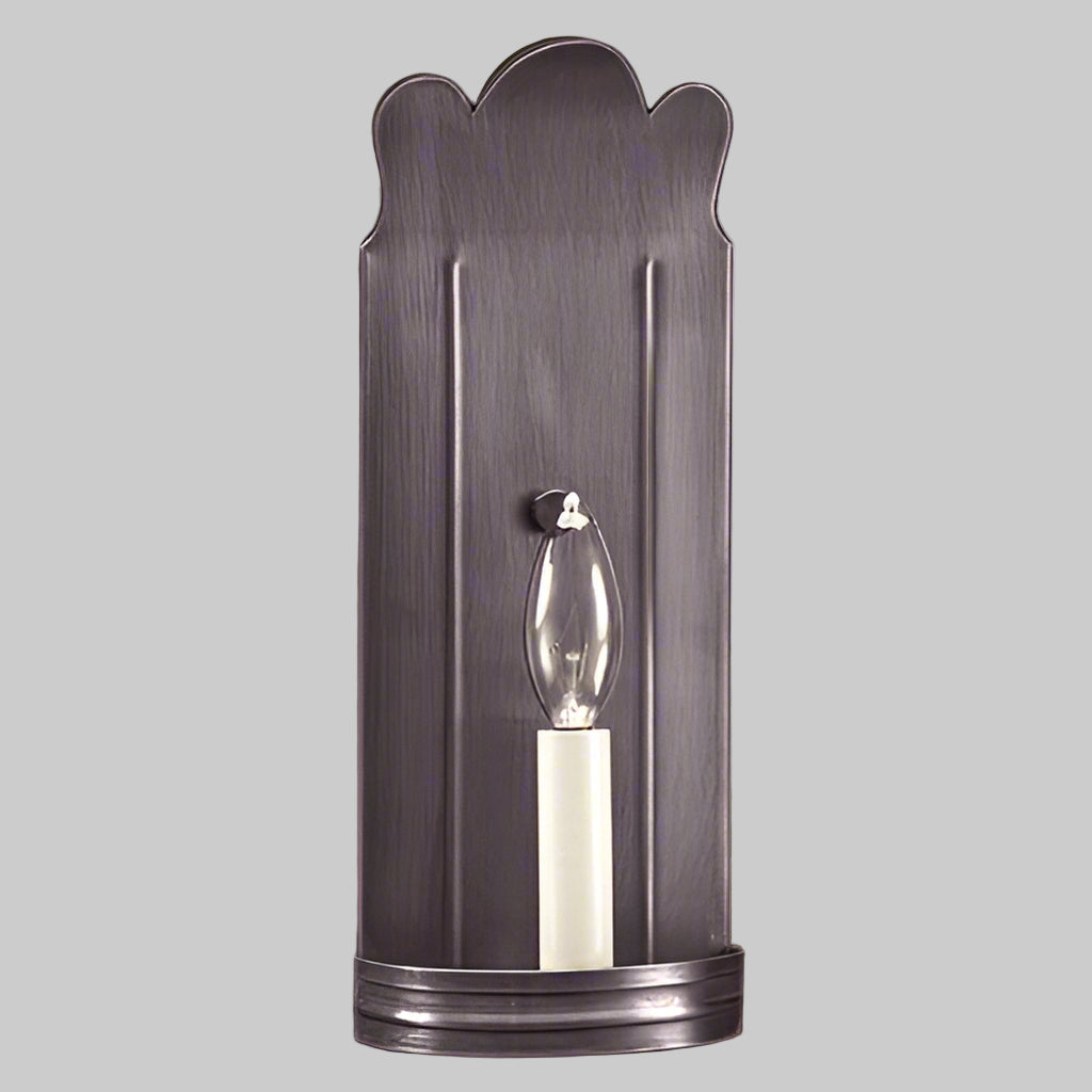 Decorative wall sconce with scalloped design on a beige wall