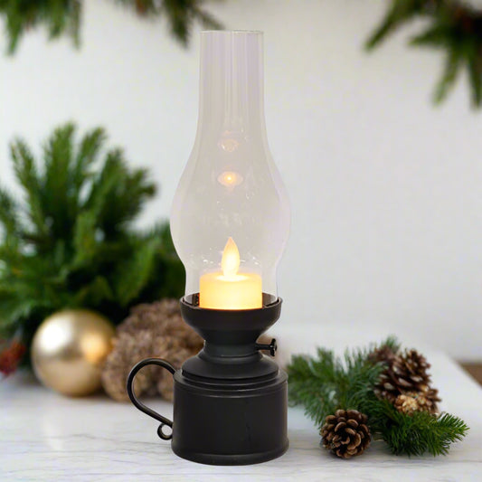Decorative lantern with a candle surrounded by Christmas decorations on a white surface.