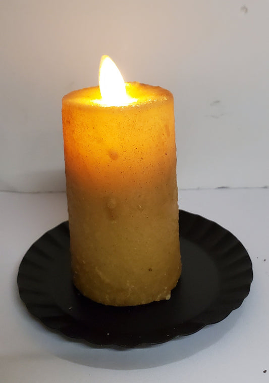 A realistic moving flame mini pillar candle burnt ivory in color, placed on a black dish.