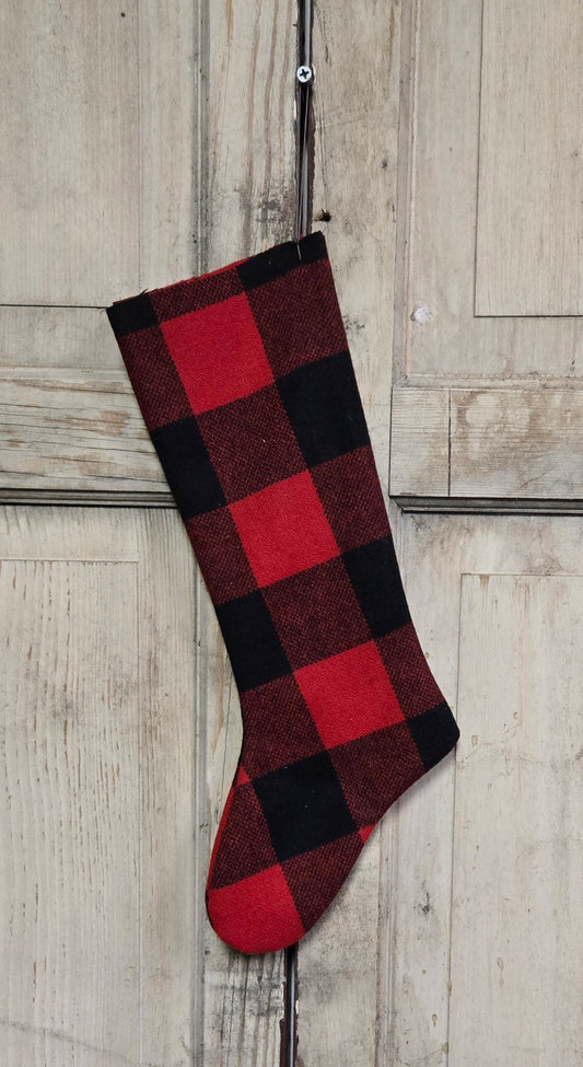 Red and black checkered stocking hanging on a wooden door.