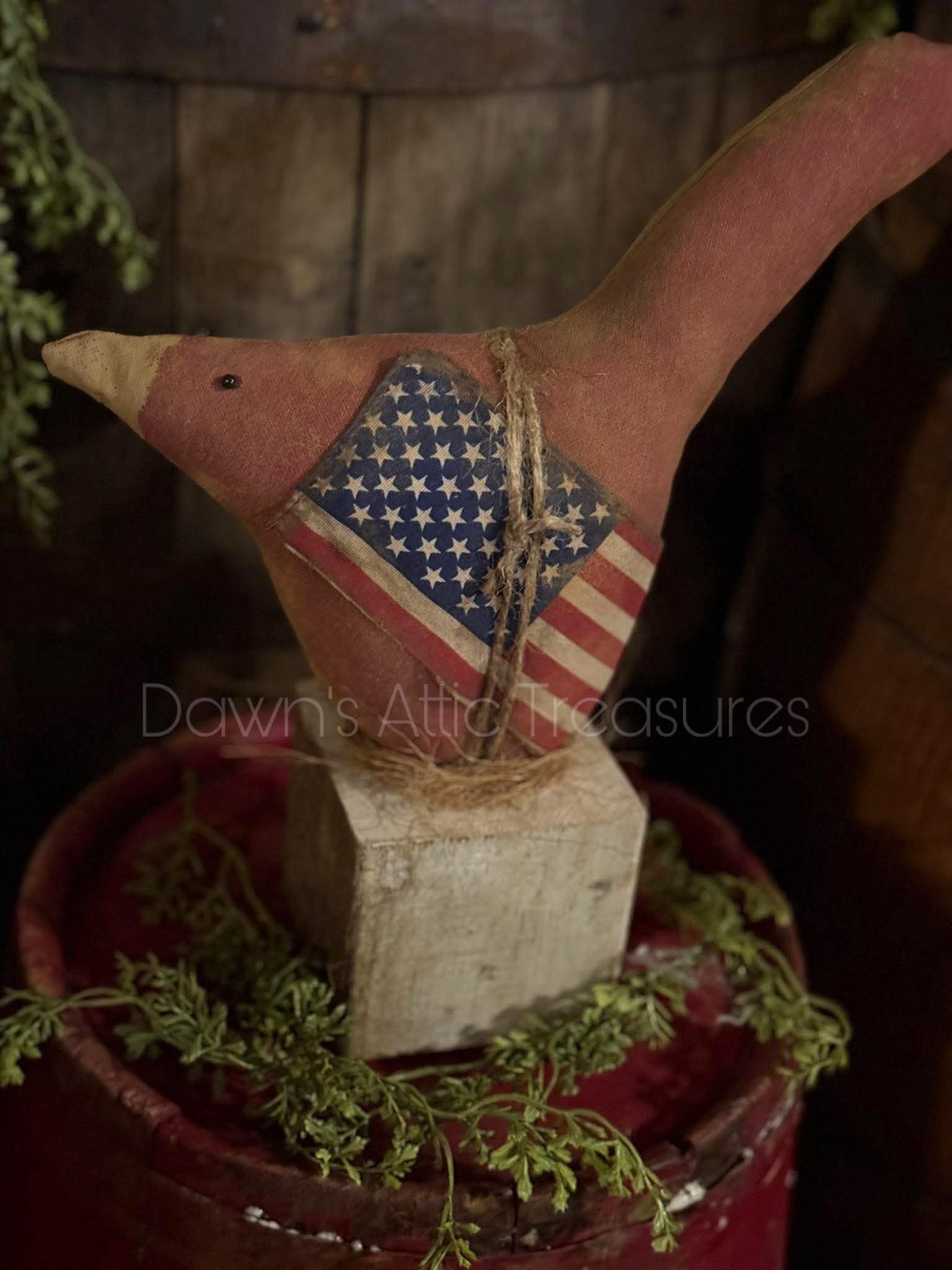 Decorative bird with American flag on a wooden block in a rustic setting