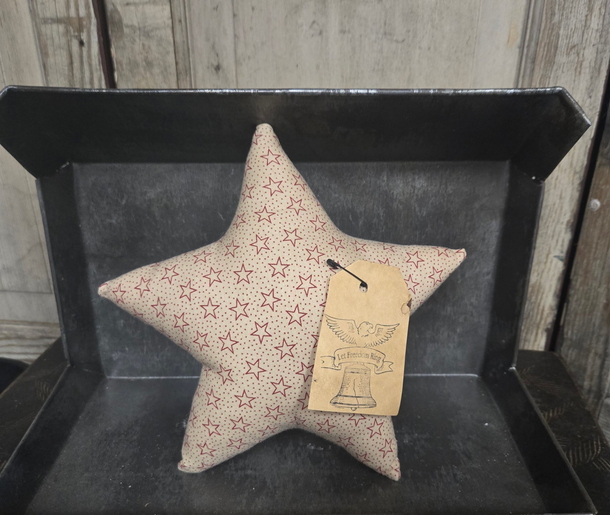 Star-shaped pillow with star pattern on a black tray against a wooden background