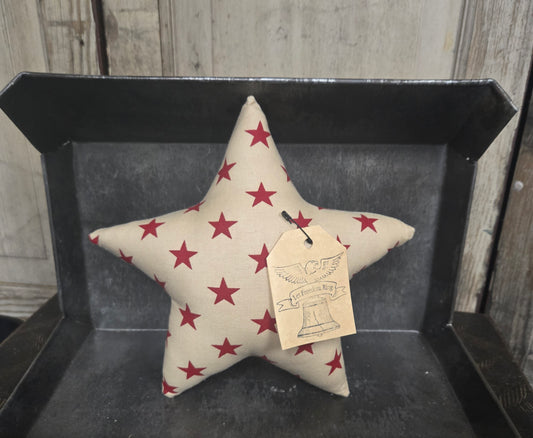 Star-shaped pillow with red star pattern on a black tray against a wooden background