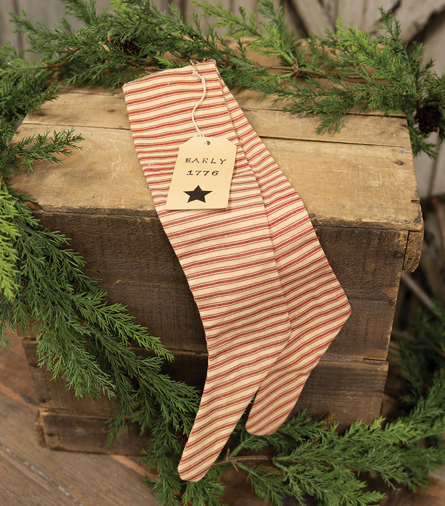 Red ticking stripe stocking ornaments on wooden crate with with greenery garland behind