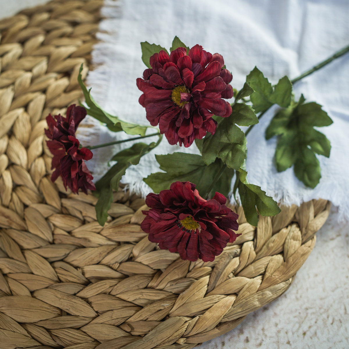 Red flowers with green leaves on a woven mat