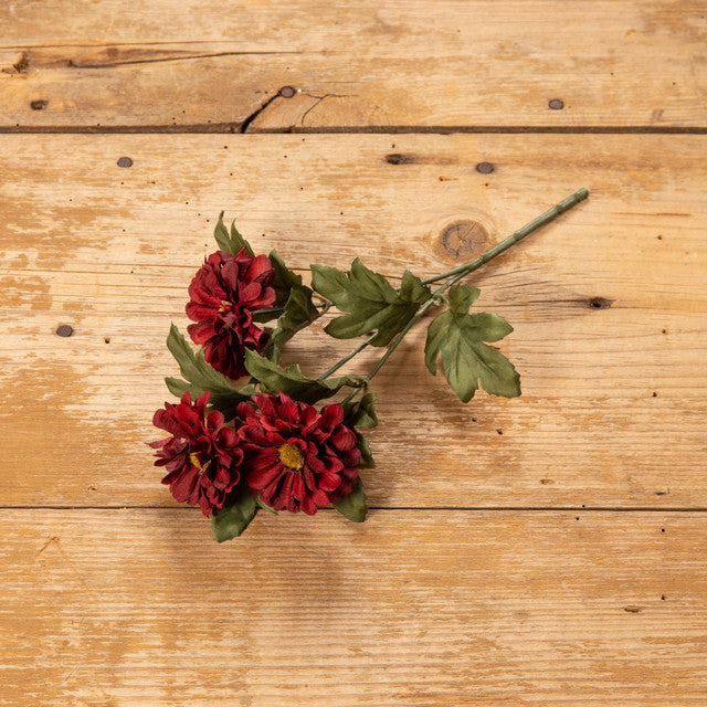 Red floral pick on wood table.