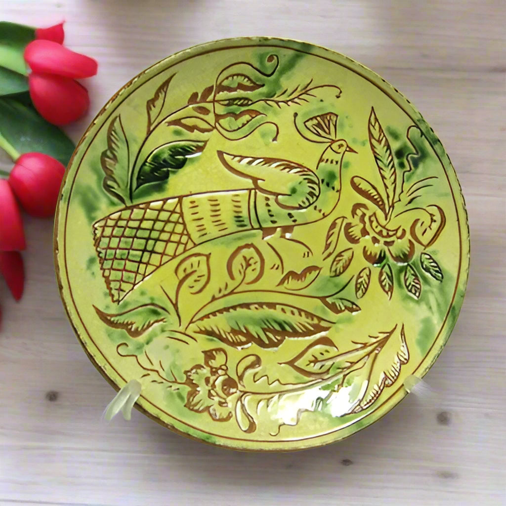 Round redware plate with bird and flower motive with yellow, brown and green tones