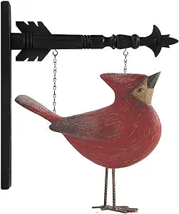 A resin figurine of a red cardinal with a head-up arrow replacement, hanging against a black background.