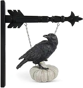 A black resin crow perched on a white pumpkin attached to a black arrow-shaped mount.