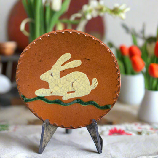 Small round redware plate with white resting bunny on grass