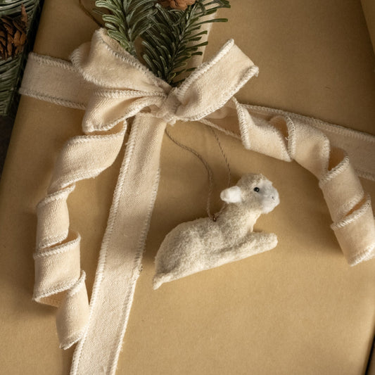 Gift wrapped in brown paper with a beige ribbon and a small white mouse ornament.