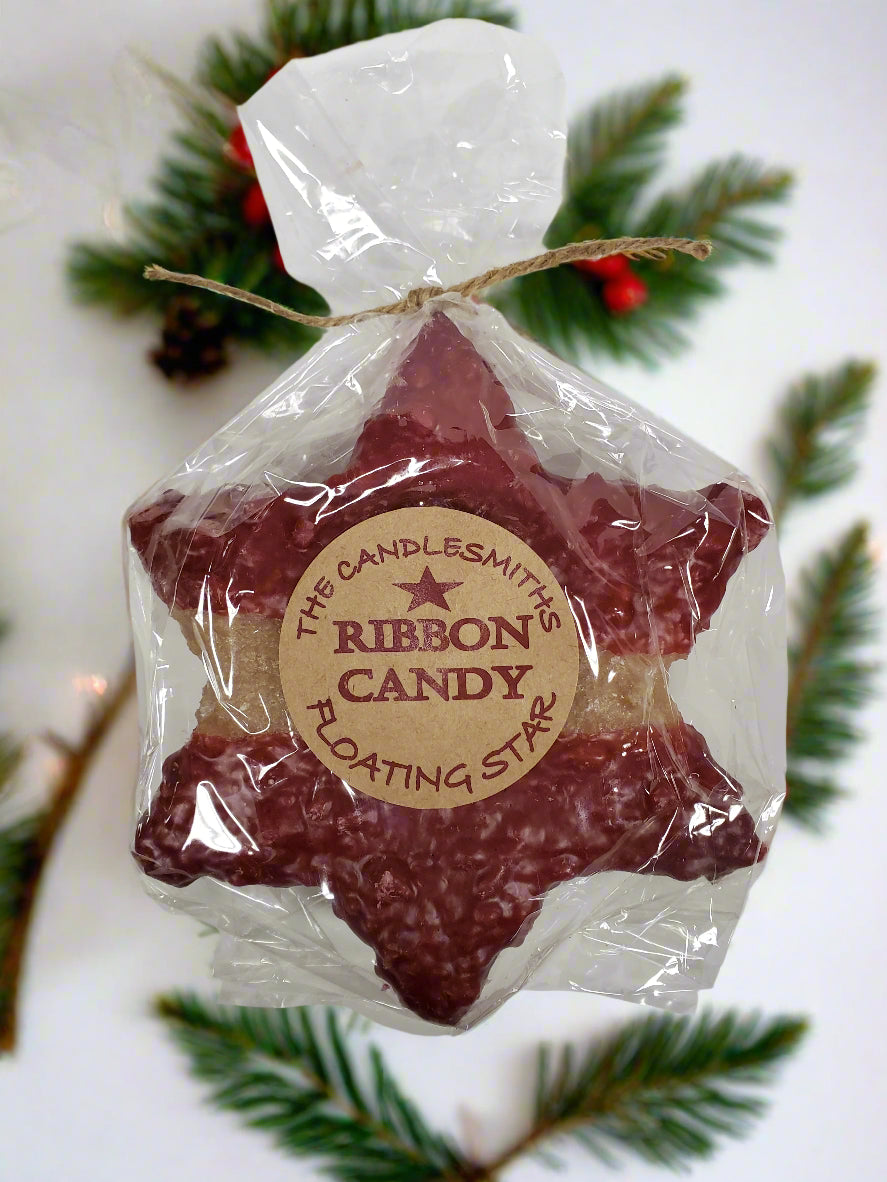 A large red star-shaped floating candle by The Candlesmith, packaged in a clear plastic bag with a label and a string attached to top.