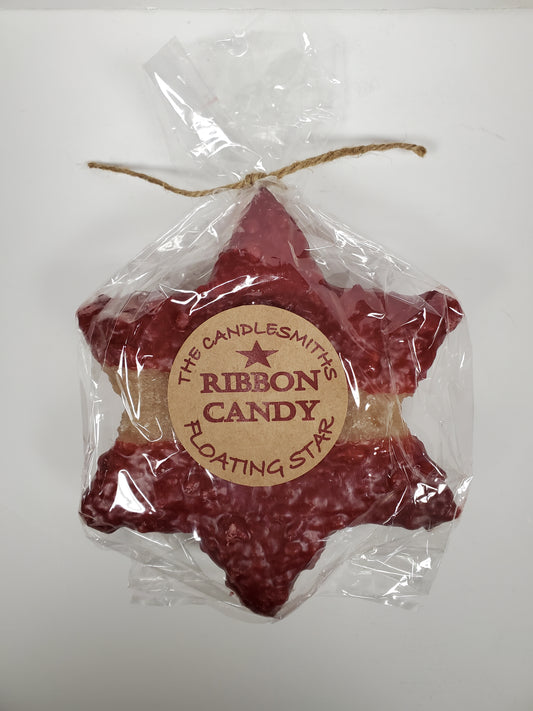 A large red star-shaped floating candle by The Candlesmith, packaged in a clear plastic bag with a label and a string attached to top.