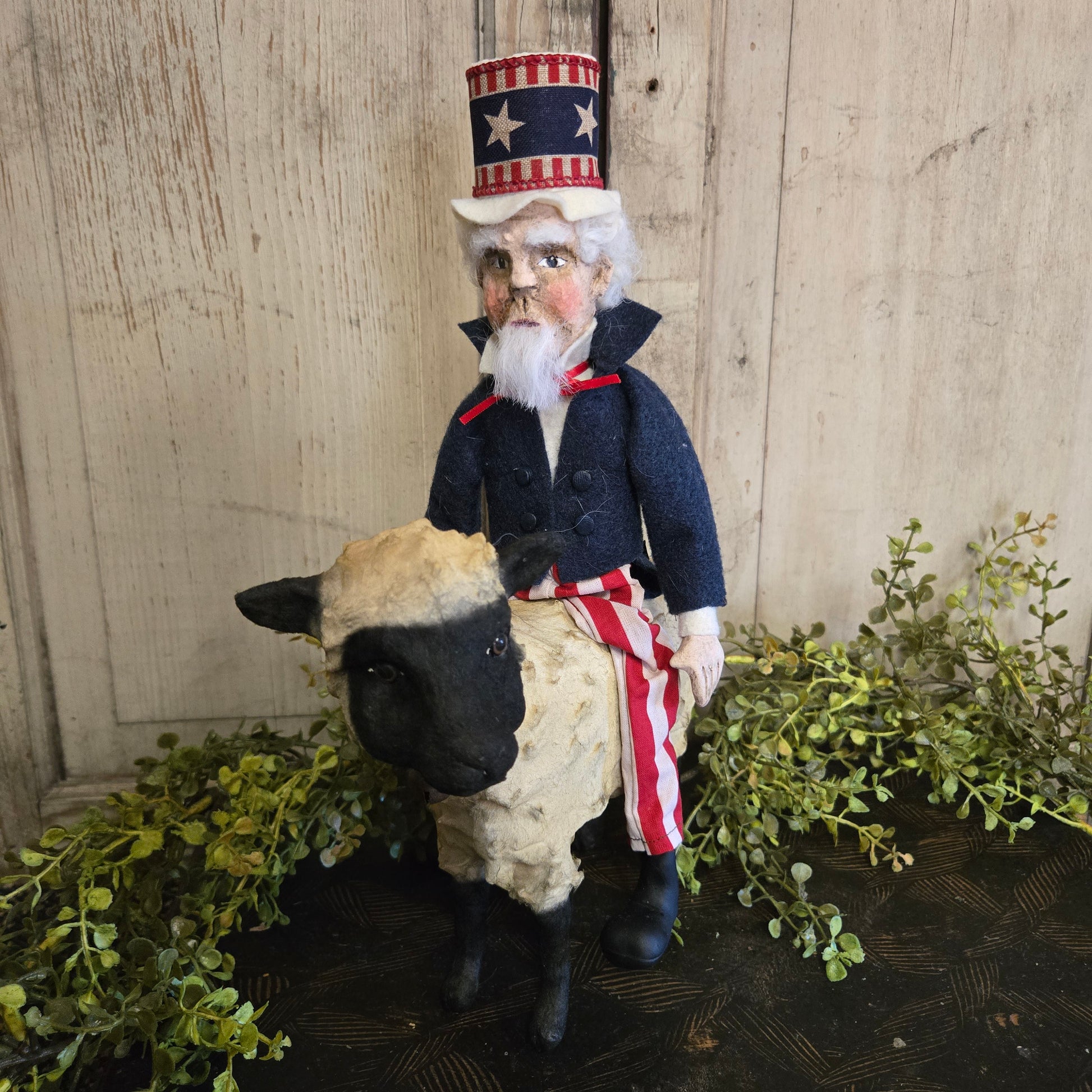 Decorative figure of a man in a patriotic outfit with a dog, standing on a wooden surface with greenery.