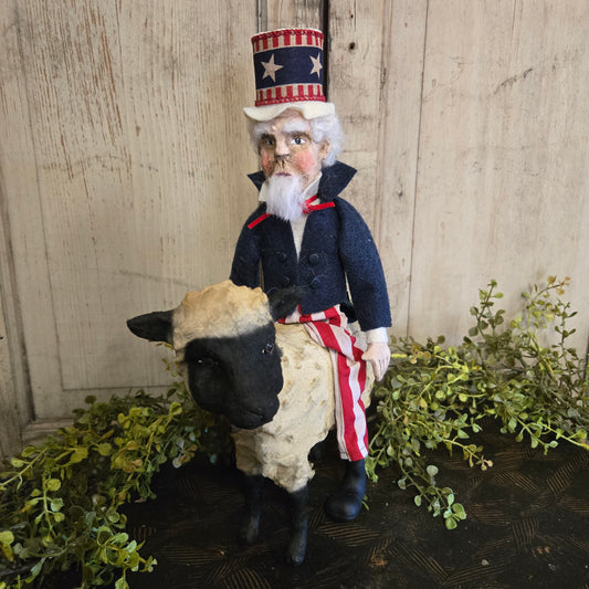 Decorative figure of a man in a patriotic outfit with a dog, standing on a wooden surface with greenery.