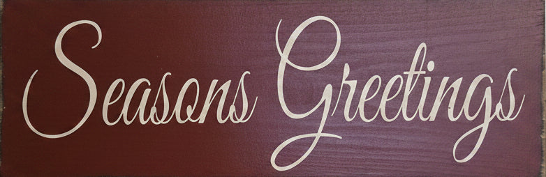 A rectangular rustic wooden sign with 'Seasons Greetings' in white cursive script.