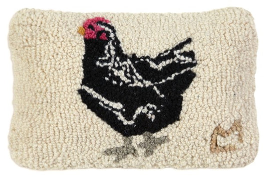 A hooked wool pillow shaped like a black hen with a red comb and face, with a velveteen backing.