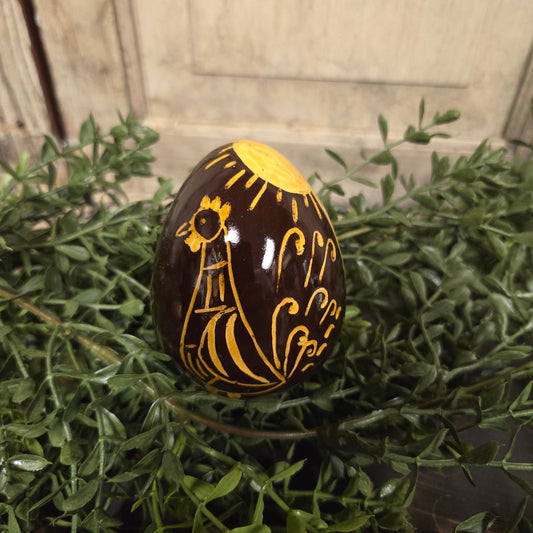 Brown redware egg with yellow glazed rooster and sun motif
