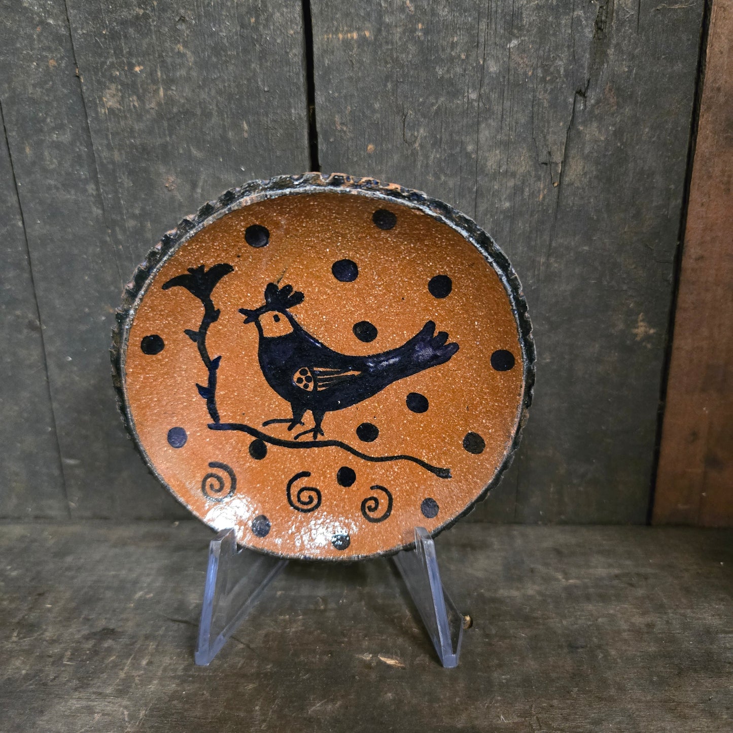 Round wooden plate with black and brown design on a dark wooden surface
