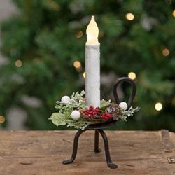 Decorative candle holder with a lit candle on a wooden surface, Christmas tree in the background