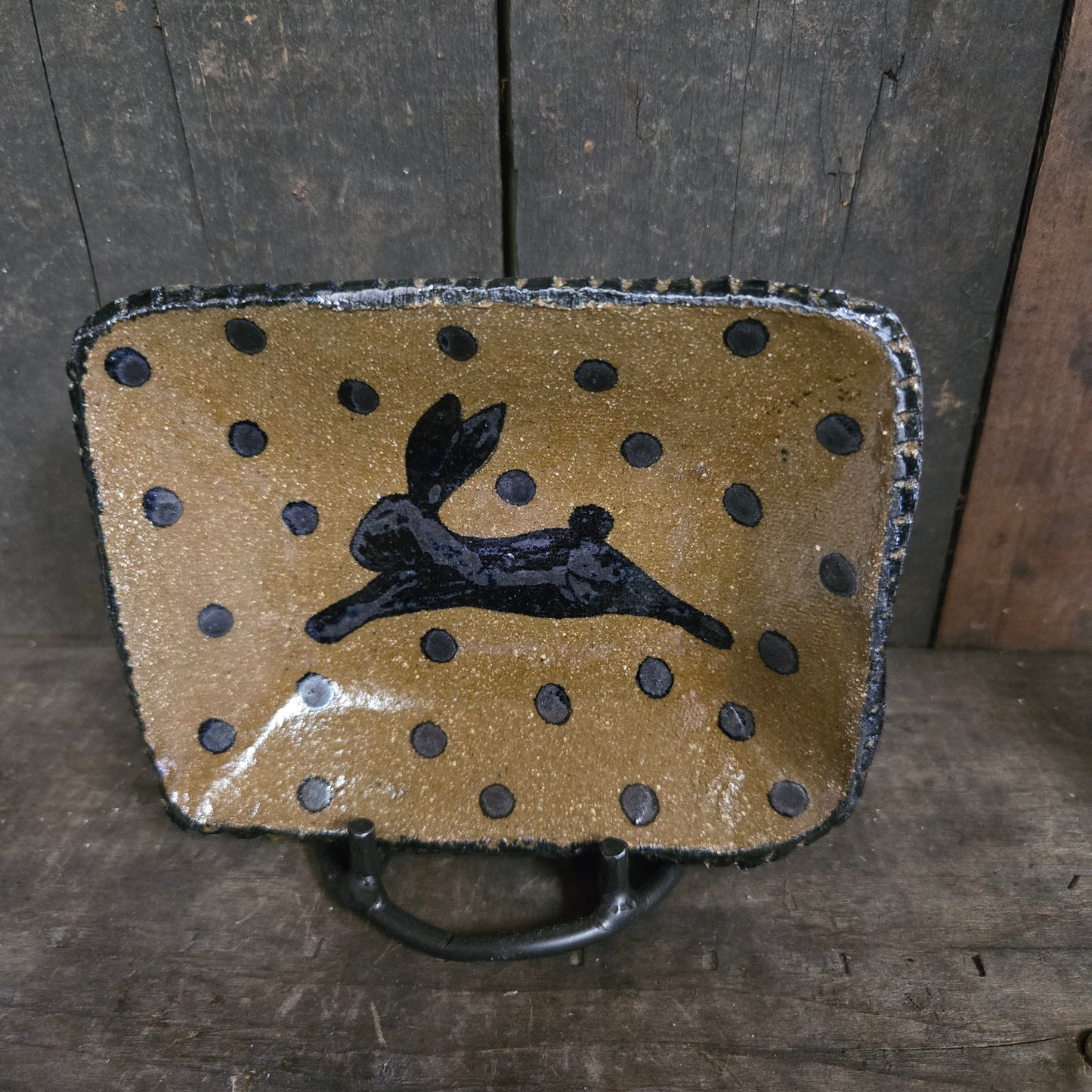 Decorative ceramic plate with black polka dots and a black silhouette of a person on a wooden surface