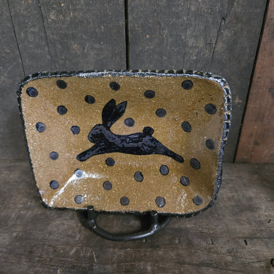 Decorative ceramic plate with black polka dots and a black silhouette of a person on a wooden surface