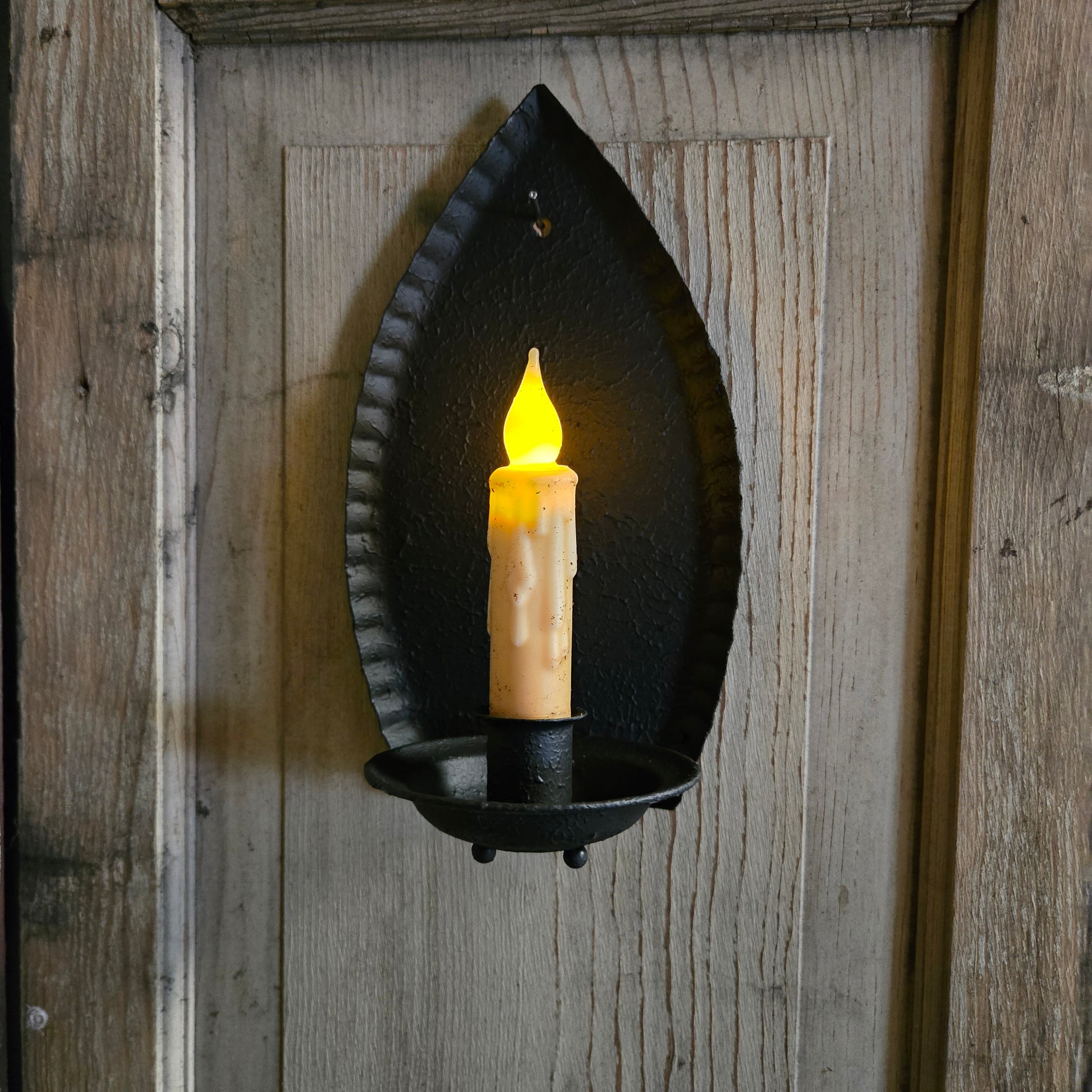 Decorative wall sconce with a candle-like light on a wooden background