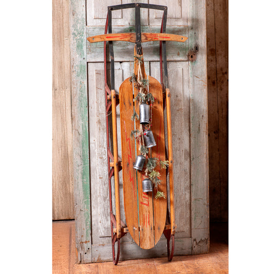 Rustic hanging four bells displayed on an antique wooden sled