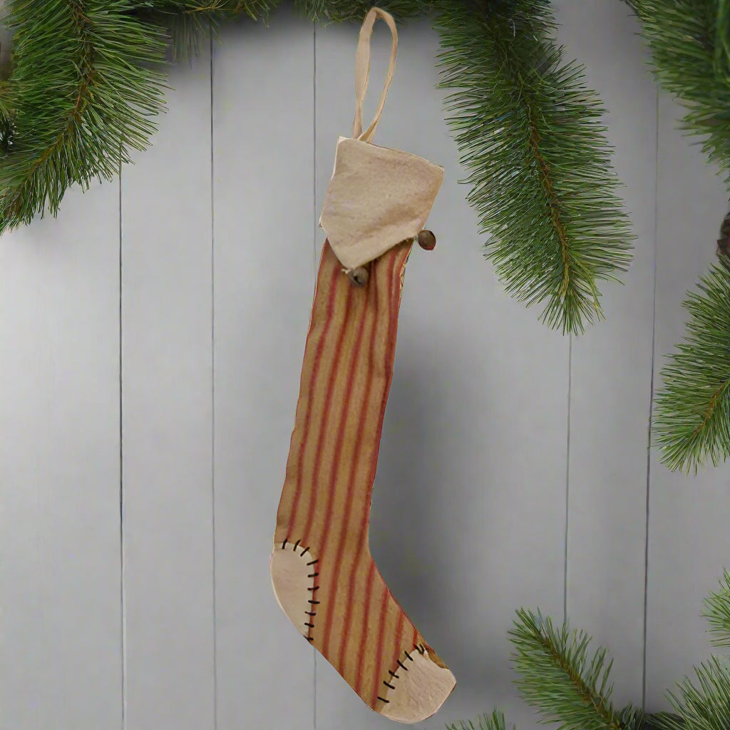 A rustic holiday stocking with striped pattern and bell accents.