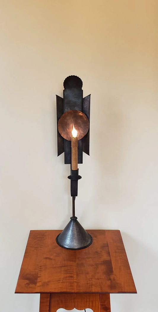 Decorative wall sconce with a lit candle on a wooden pedestal against a plain wall.
