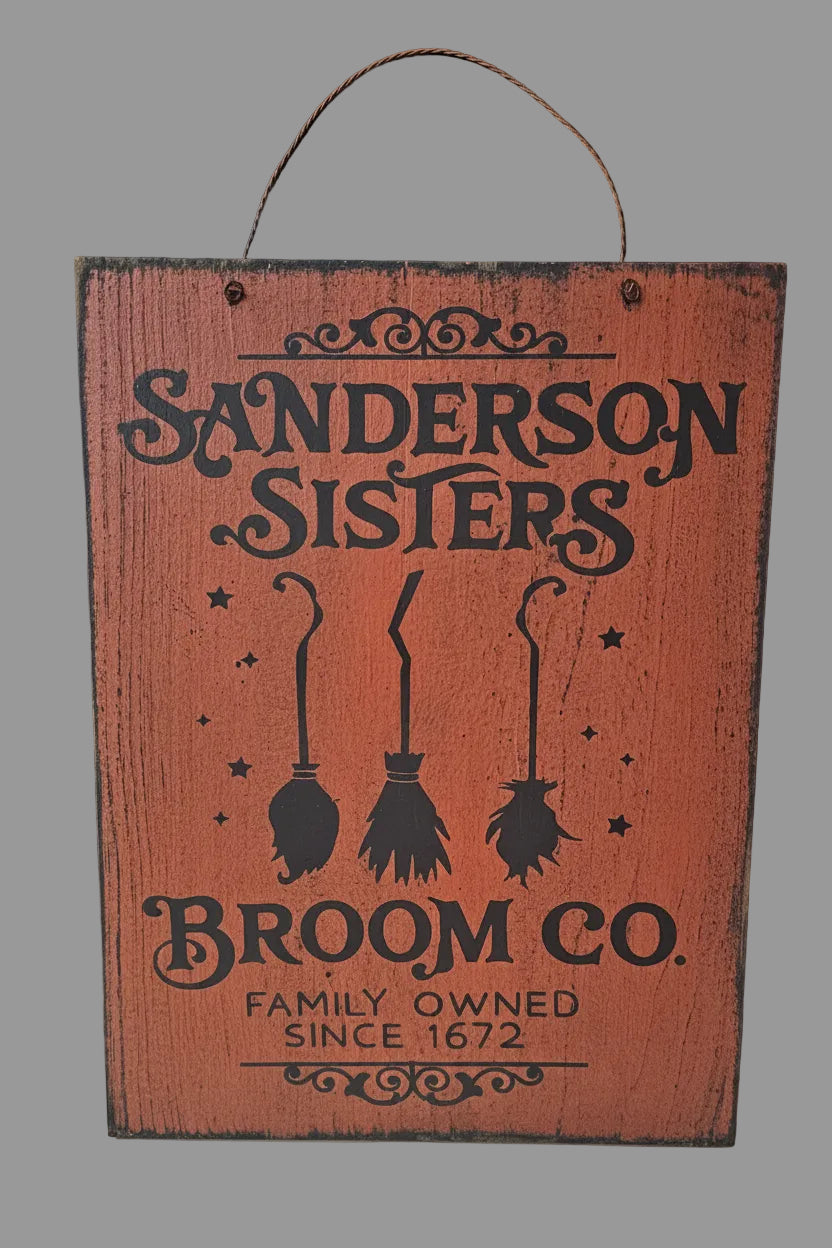 Wooden sign with 'Sanderson Sisters Broom Co.' design on a dark background