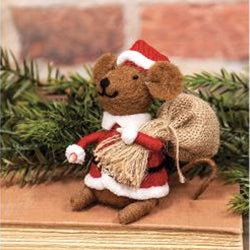 Decorative mouse figurine in a Santa outfit with a bundle of hay, placed on a wooden surface with a Christmas tree in the background.