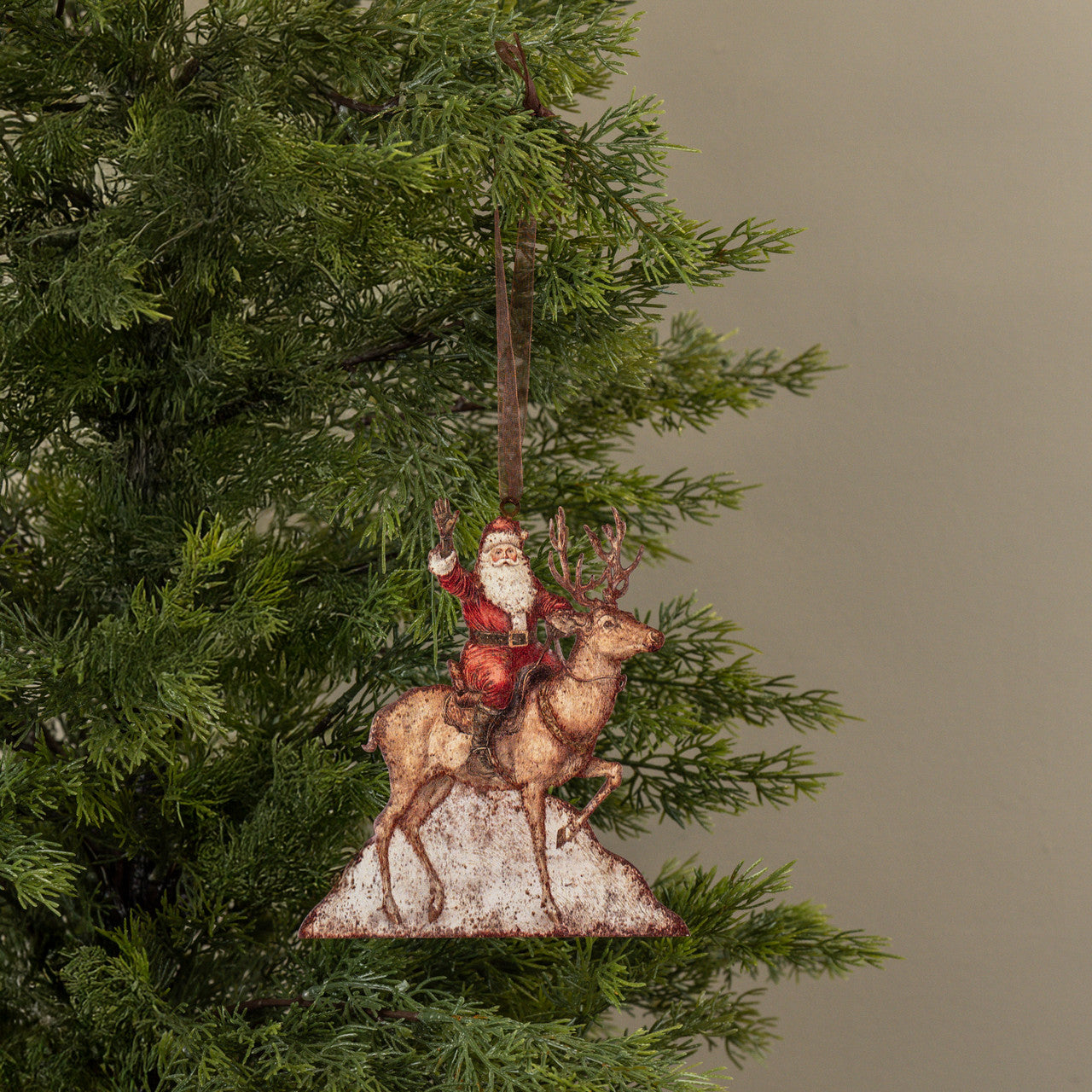 Christmas ornament of Santa riding a reindeer on a tree