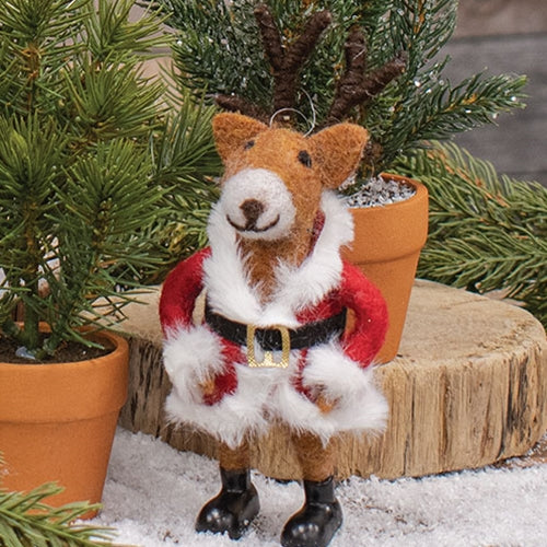 Plush fox toy in a Santa outfit with potted plants and snow-like surface