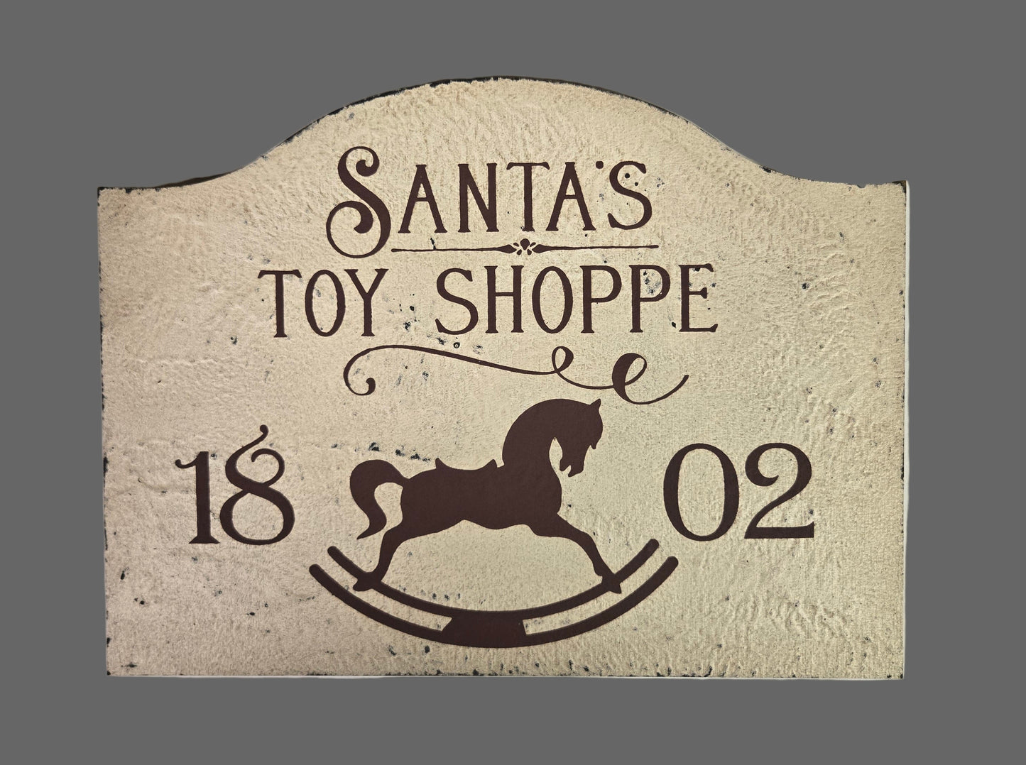 Decorative sign with 'Santa's Toy Shoppe' text and a reindeer silhouette on a textured background.