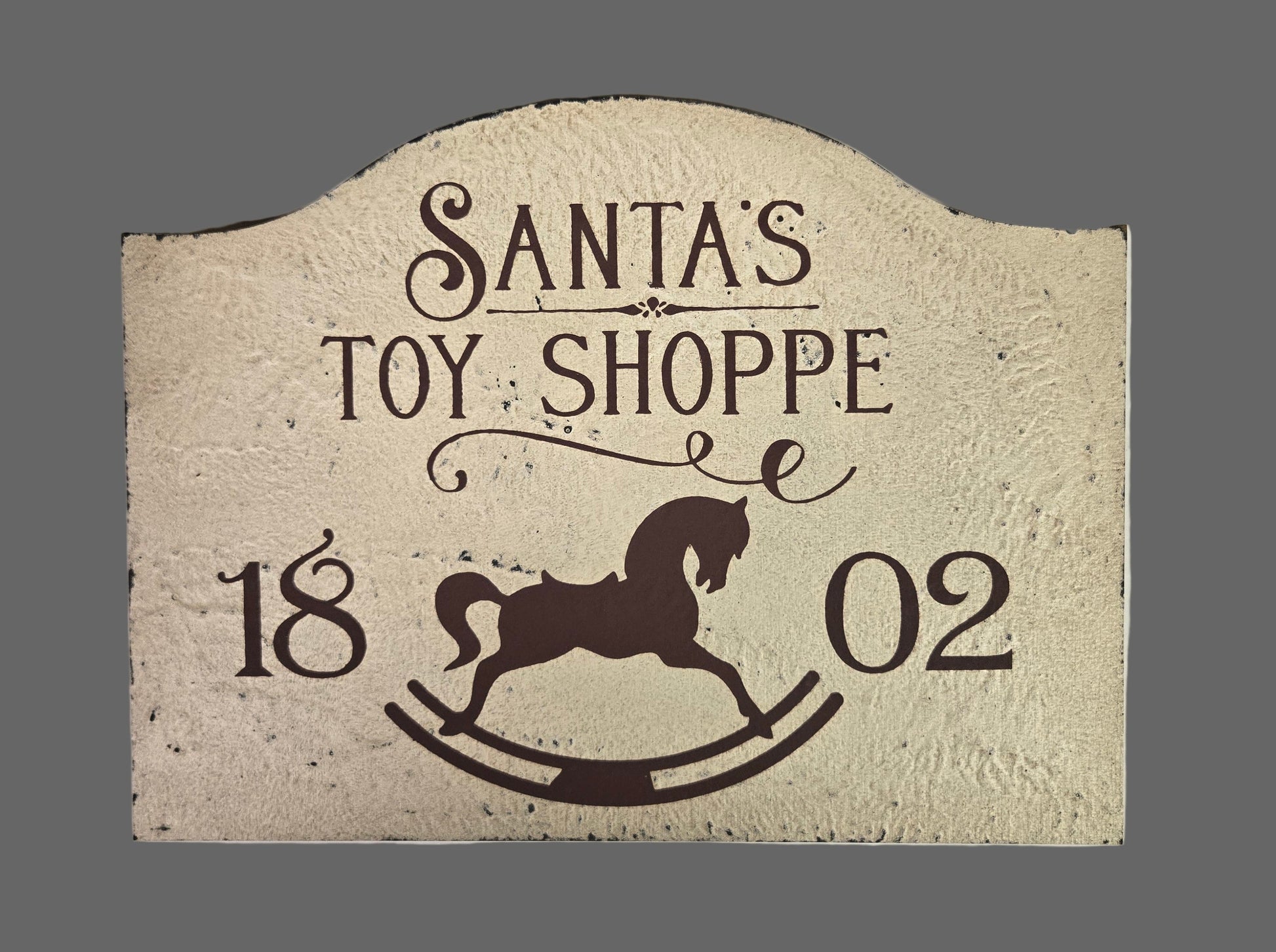Decorative sign with 'Santa's Toy Shoppe' text and a reindeer silhouette on a textured background.