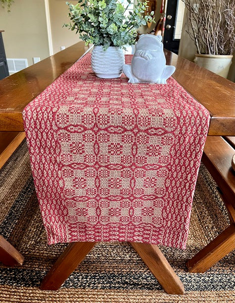 Red patterned table runner on a wooden table with decorative items.