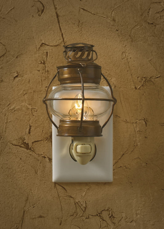 A sea lantern-style night light with a glass enclosure and metal frame, mounted on a wall, emitting a warm glow.