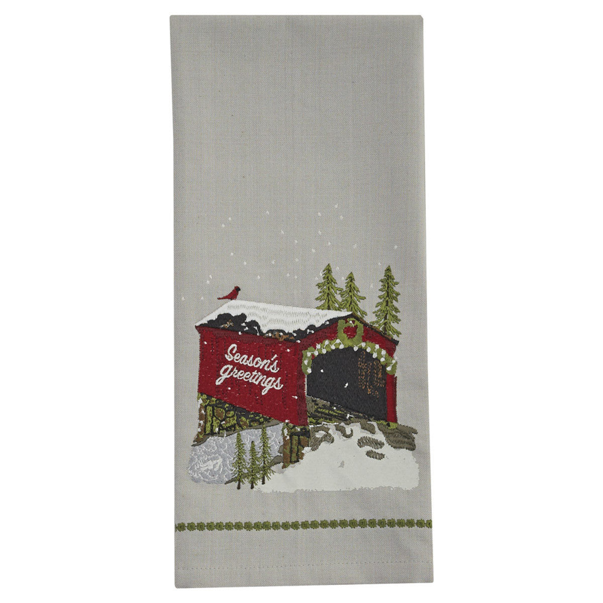 A dishtowel with a Christmas-themed design featuring a covered bridge, evergreen trees, and the text 'Seasons Greetings'.