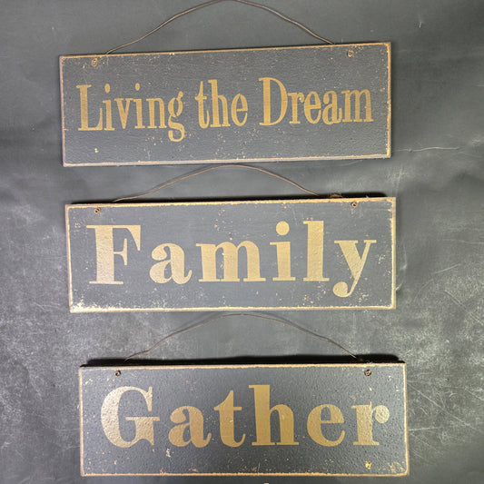 Three wooden signs with gold text on a dark background