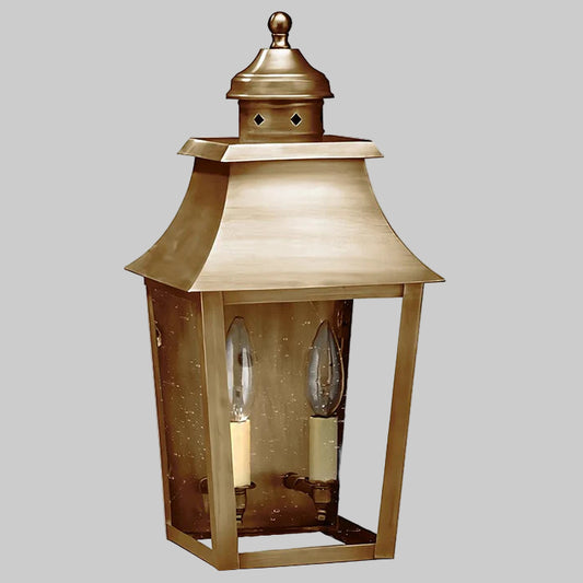 Brass outdoor lantern with two candle-like lights on a gray background