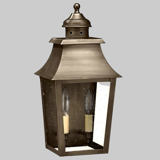 Bronze outdoor lantern with two candle-like lights on a gray background