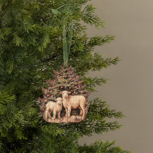 Decorative ornament with sheep and a tree hanging on a Christmas tree.
